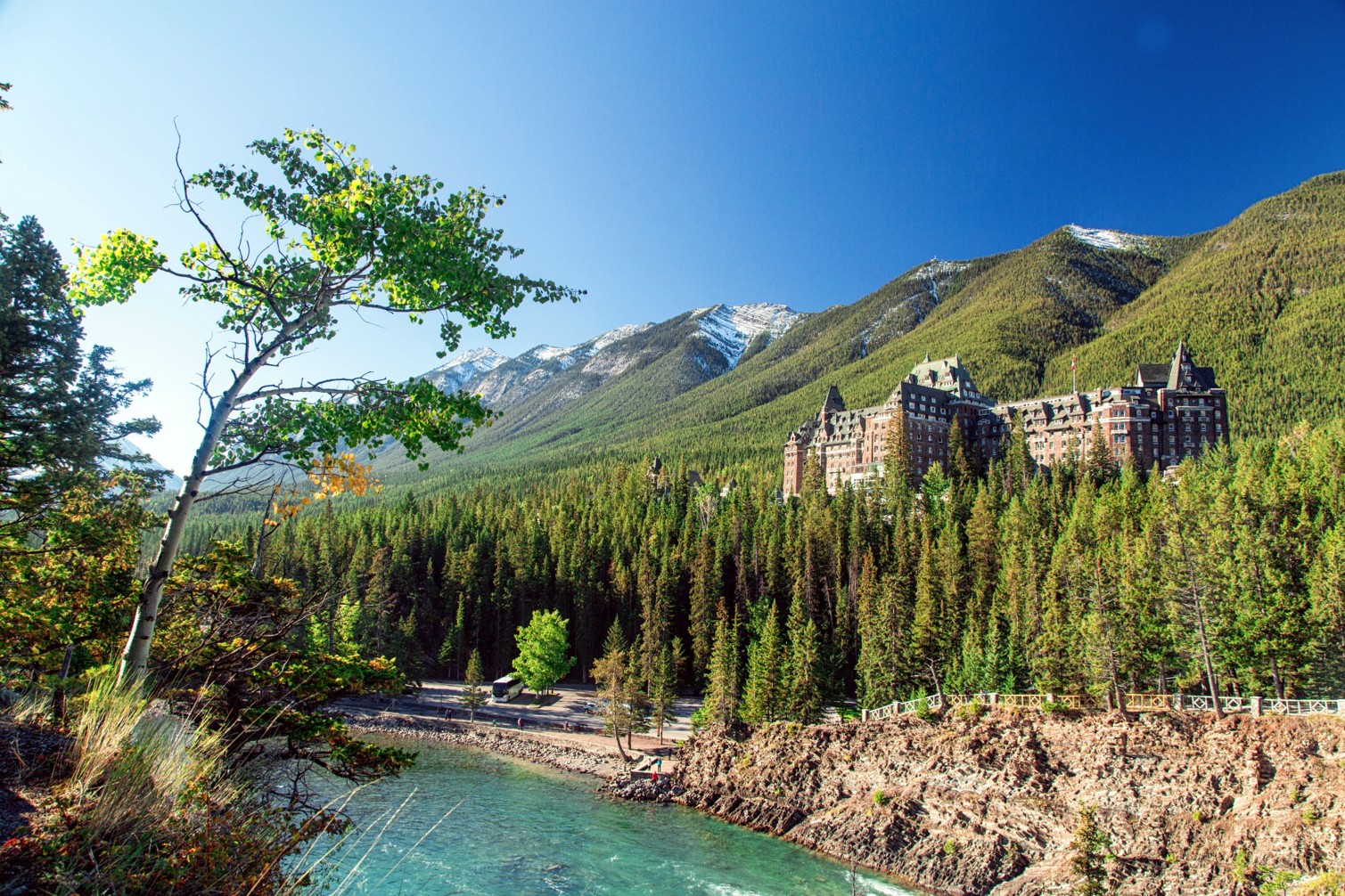 Hotel Fairmont Banff Springs frente al río Bow en las Montañas Rocosas de Canadá bajo un cielo despejado.