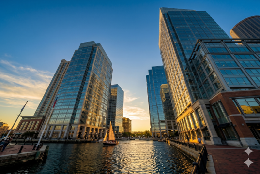 Vista panorámica de los rascacielos del Waterfront de Boston durante la hora dorada con un velero navegando, para los programas de Nilen Travel.